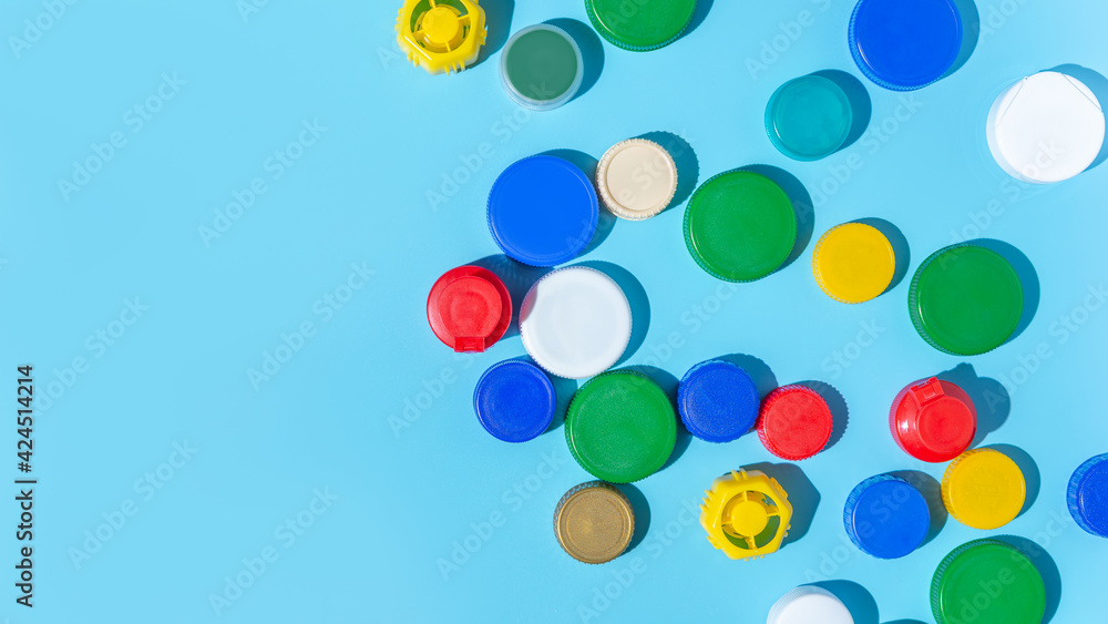 Colorful plastic bottle caps on a blue background, collecting plastic for recycling and reuse. copy space