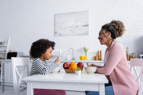 side view of african american mom and daughter looking at each other during breakfast