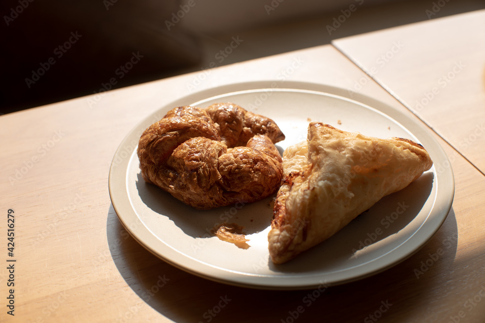 Morning croissant and pie in white plate on wooden table Morning croissant and pie in white plate on wooden table