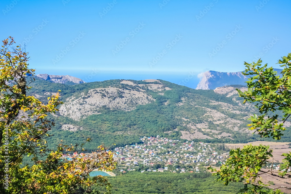 A small town at the foot of the mountains. ?illage in a valley between the mountains. Rural landscape. Wooden roofs of houses. Crimea