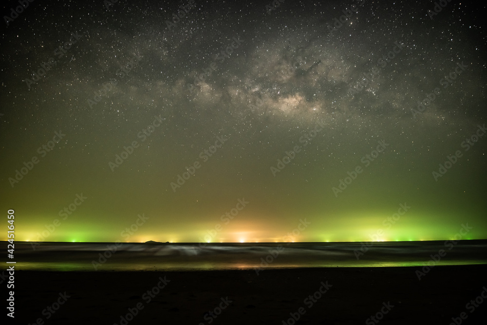 sea scape with light of fishing boats under the milky way on horizon stock photo