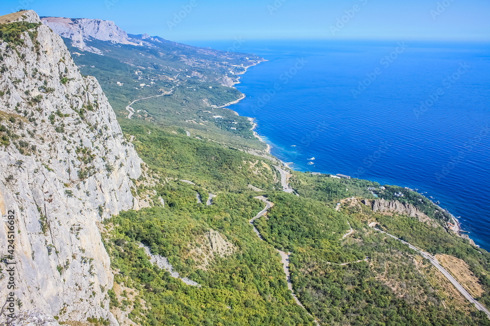 Mediterranean landscape. Forested rocks of the Black Sea coast of the southern coast of the Crimean Peninsula on a clear sunny day. View down from the rocky mountains to the sea