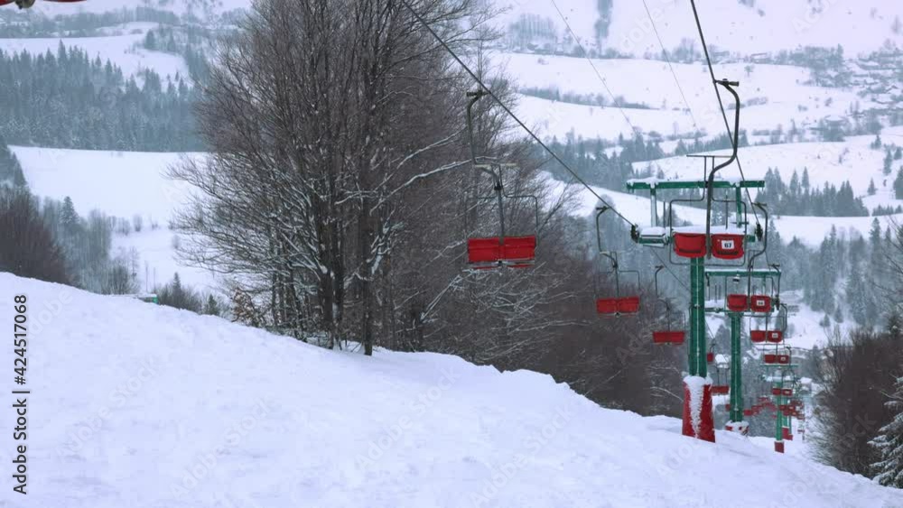 View of the colored lift against the background of a mountain spruce forest and gray sky in the beautiful Carpathians