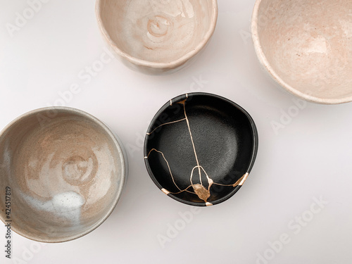 Black kintsugi bowl with gold scars, the beauty of being different. Gold scars and Japanese raku pottery