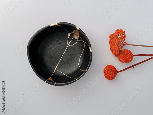 Canvas-taulu Black Kintsugi bowl with red flowers, Japanese restoration technique with gold s