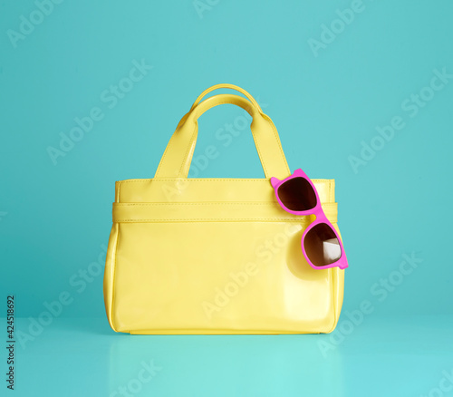 Wallpaper Mural Yellow handbag purse with pink sunglasses isolated on blue background.  Torontodigital.ca