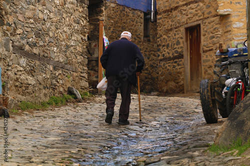 selective focus. The old man, who takes his bread from the market, goes to his house through the narrow streets of Bursa. The melting snow waters flow from the mountain in the historical streets.
