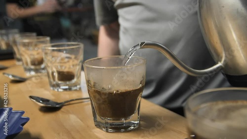 Pouring hot steamy water for coffee cupping taste test, slow motion close up photo