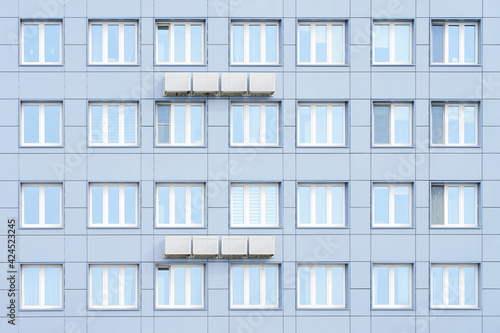 The facade of a residential building, lined with aluminum panels. Air conditioners hang on the facade. Copy space.