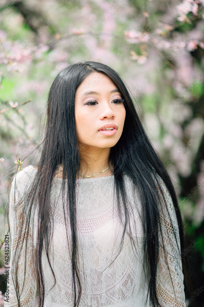 portrait of beautiful young asian woman with blooming cherry blossoms sakura flowers. Enjoying of spring. flying petals of cherry portrait of beautiful young asian woman with blooming cherry blossoms sakura flowers. Enjoying of spring. flying petals of cherry