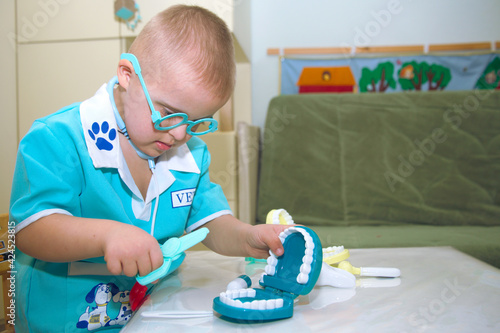 Quadro su tela A boy with Down syndrome plays a role-playing game, a genetically ill disabled child in a doctor's costume, a portrait of special children, genetic abnormalities
