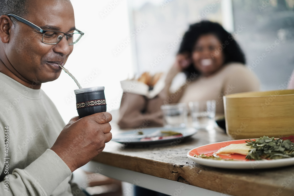 Happy black father drinking yerba mate during lunch at home - Main focus on man face