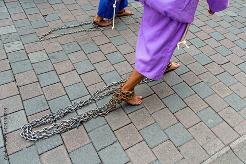 Cucurucho penitent walking barefoot with chains on the Good Friday Easter procession, Quito, Ecuador.