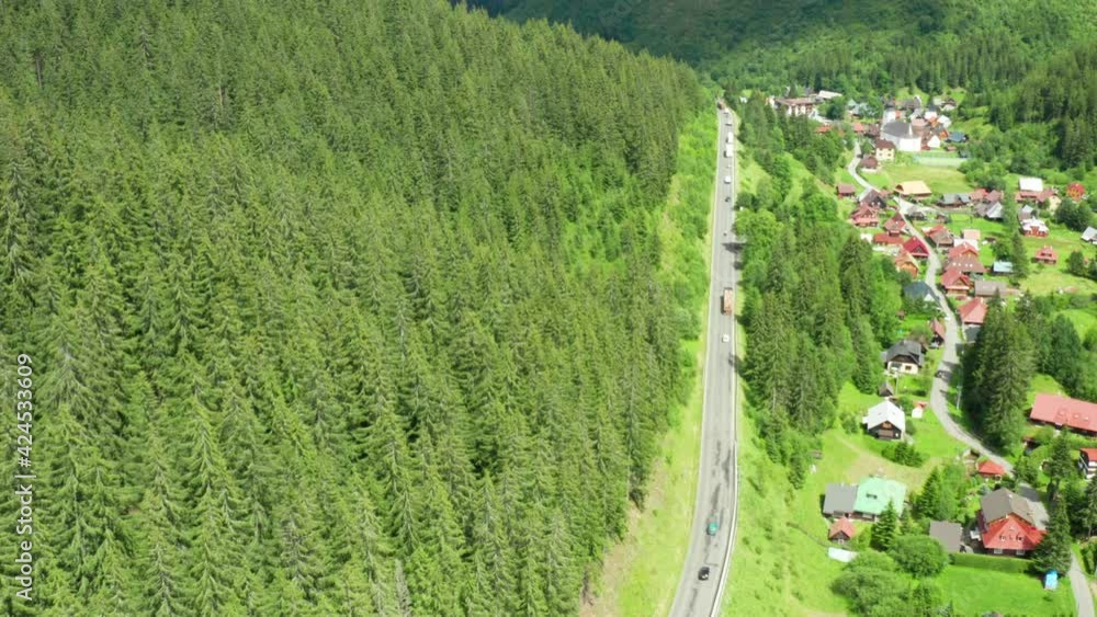 Aerial view of the road with driving cars and truck in the mountains with high green fir, foliar, pine or spruce trees. Aerial view of the road with driving cars and truck in the mountains with high green fir, foliar, pine or spruce trees.