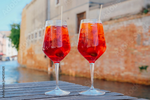 Two glasses of Spritz Veneziano cocktail served near the Venetian canal.  Popular italian summer aperitif drink. Venice background.