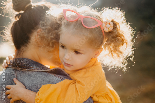 Young brunette mother holding his little curly daughter photo