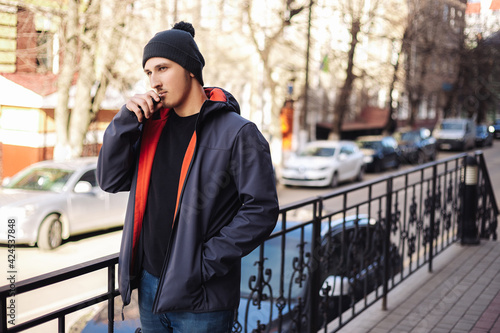 Obraz na plátně Young adult man outside and smoking tobacco device electronic cigarette heater
