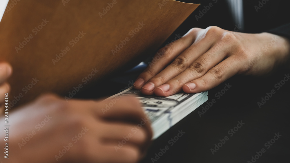 Businesswoman hand holding bribe money to government officials sign contracts for business projects, put money under envelope, ideas of corruption and anti-bribery