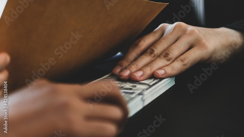 Businesswoman hand holding bribe money to government officials sign contracts for business projects, put money under envelope, ideas of corruption and anti-bribery © Lucky7Trader