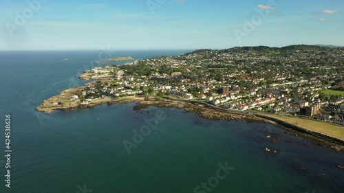 Sandycove Coastline, Dun Laoghaire Rathdown, Dublin, Ireland. Covid 19, June 2020. Drone pulls backward, with views of Forty Foot, Martello Tower, Bullock Harbour, Dalkey Island, and Killiney Hill. photo