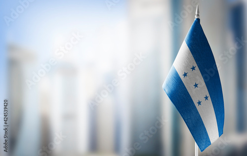 A small flag of Honduras on the background of a blurred background photo