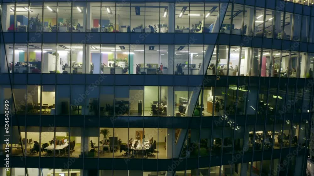 A view from a drone on the windows of offices in a skyscraper building at night. close-up 4k resolution. Drone shot at a skyscraper with offices and people working with computers in the offices A view from a drone on the windows of offices in a skyscraper building at night. close-up 4k resolution. Drone shot at a skyscraper with offices and people working with computers in the offices