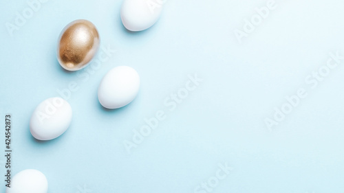 Easter luxury. Golden  white colour egg on pastel blue background in Happy Easter decoration. Flat lay  top view.