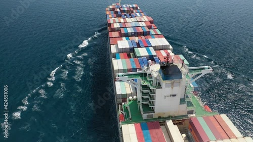 Aerial drone top view video of fully loaded container ship cruising open ocean sea for logistics import export, shipping or transportation