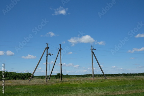 Three large poles of power lines in the field.