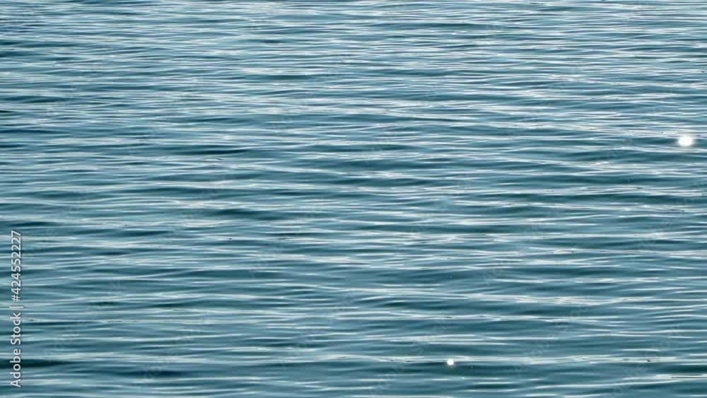 Beautiful sea surface with calm waves and sun rays shining and reflecting in the water Beautiful sea surface with calm waves and sun rays shining and reflecting in the water