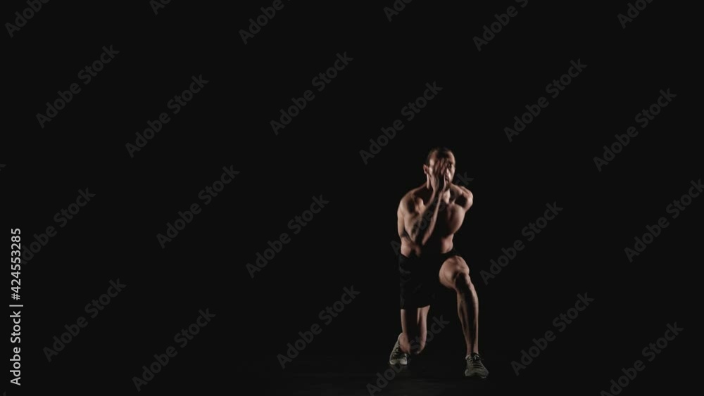 Sporty man doing physical exercises on a black background. Slow motion Sporty man doing physical exercises on a black background. Slow motion