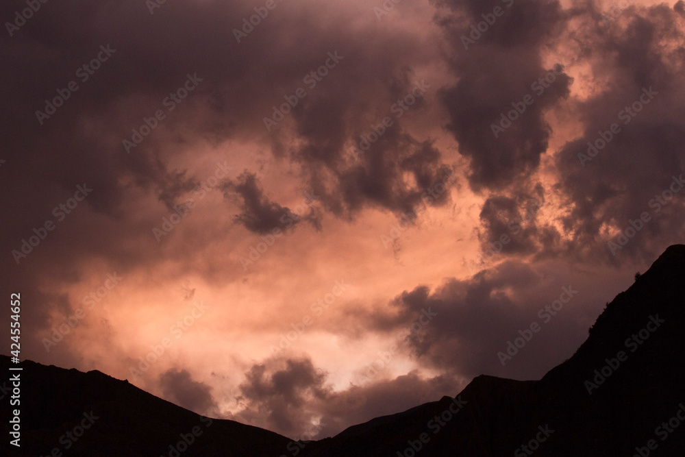 Cloudscape. Dramatic sky with colorful clouds and the mountains dark silhouette at sunset. Cloudscape. Dramatic sky with colorful clouds and the mountains dark silhouette at sunset.