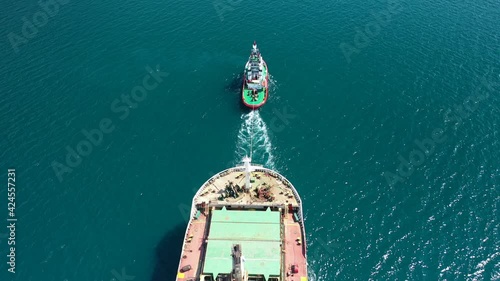 Aerial drone video of cargo carrier tanker leaving industrial port with the help of tug boats for Mediterranean destination photo
