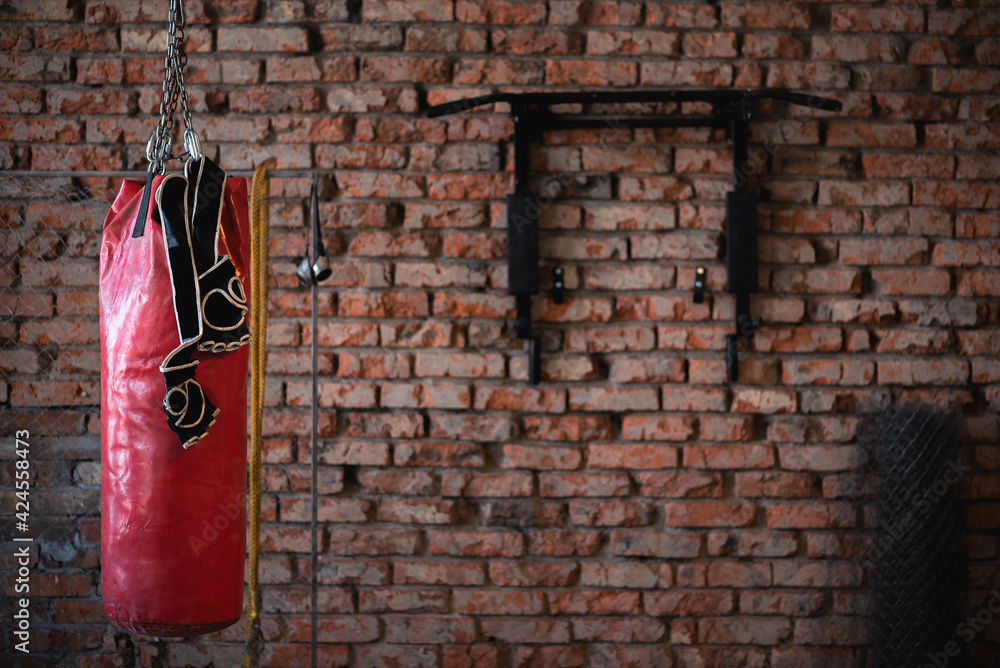 Old punching bag and boxing gloves on the brick wall background
