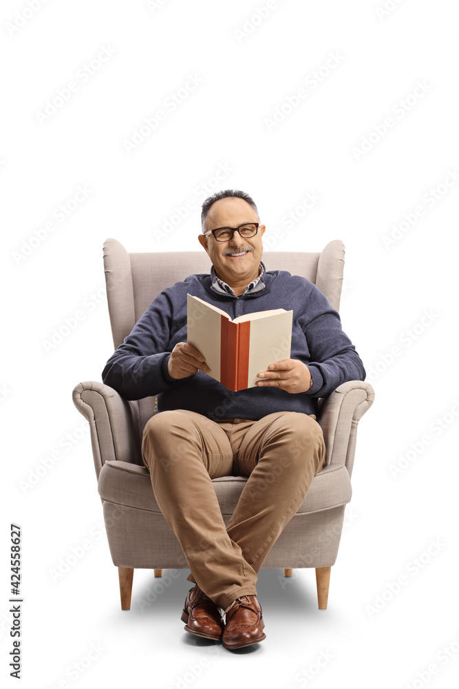 Smiling mature man sitting in an armchair and reading a book