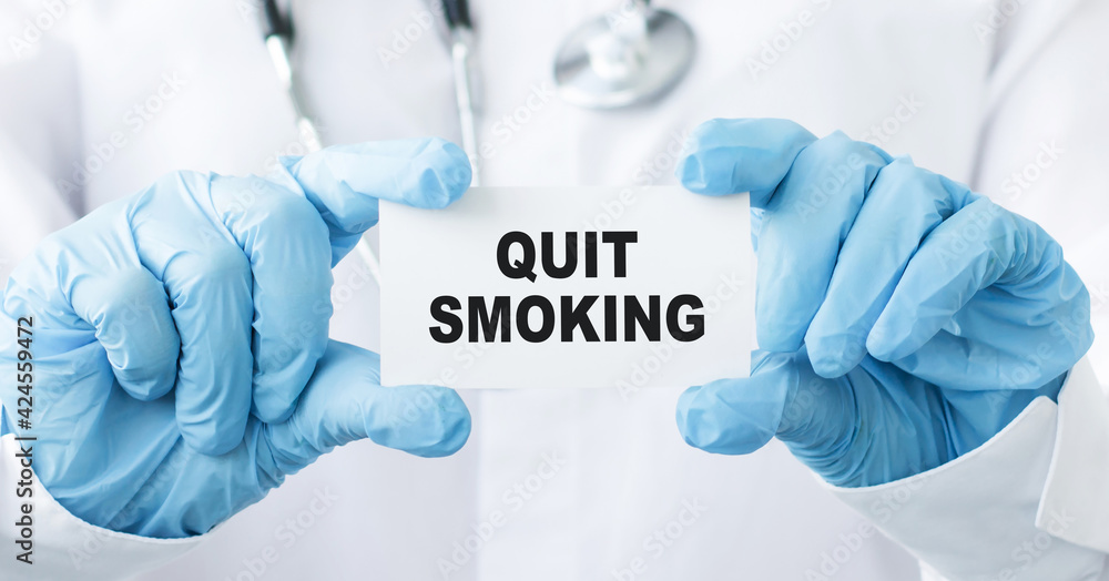 text QUIT SMOKING on card in the hands of a doctor. Medical concept text QUIT SMOKING on card in the hands of a doctor. Medical concept