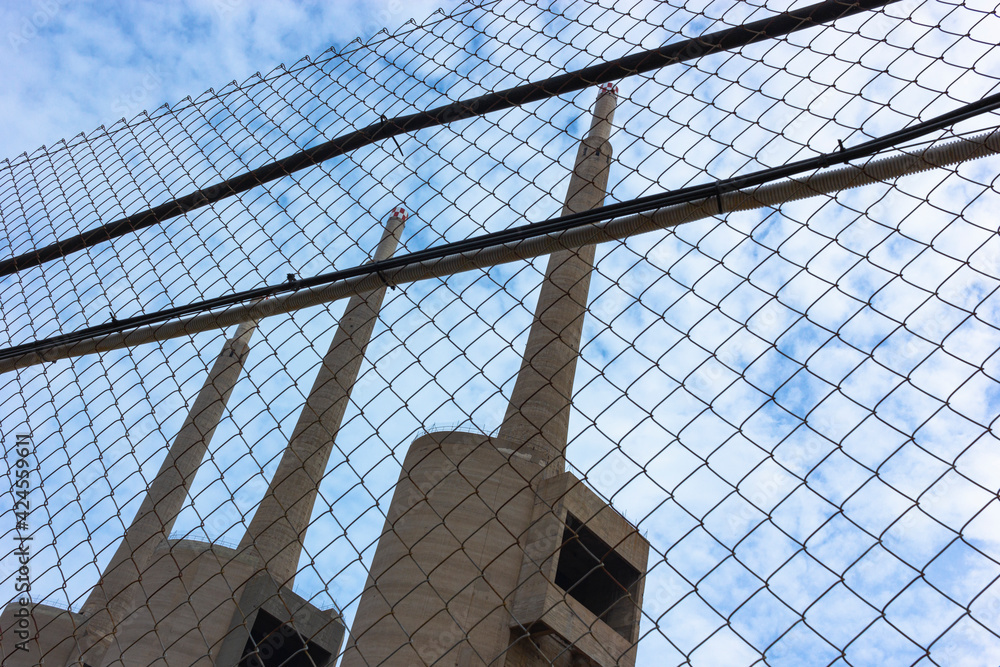Old disused thermal power plant for the production of electricity in Barcelona behind a metal fence Old disused thermal power plant for the production of electricity in Barcelona behind a metal fence