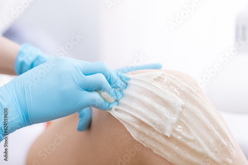 female legs hair removal with sugaring procedure in beauty salon