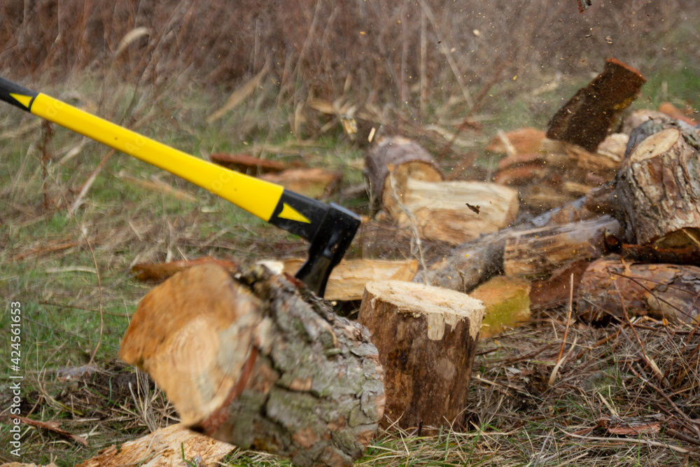 An ax with a yellow-black handle, chopping wood. An ax with a yellow-black handle, chopping wood.