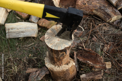 An ax with a yellow-black handle, chopping wood.