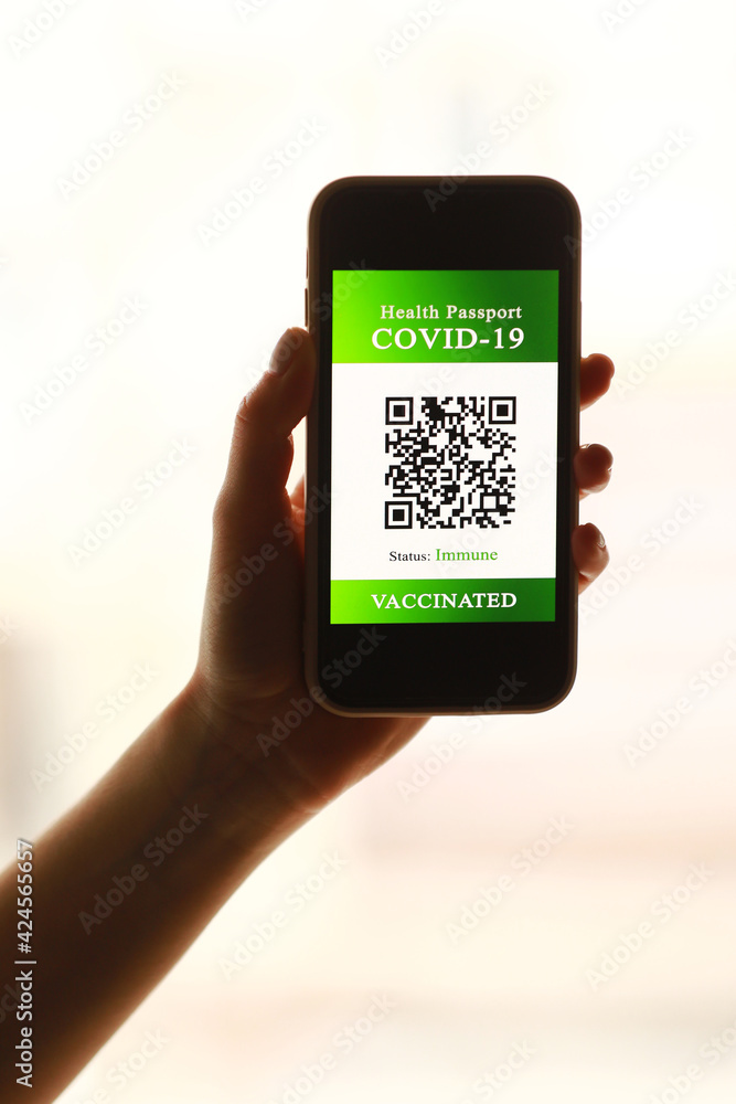 a passport and a smart phone with a certificate of vaccination against the Covid-19 disease. focus on the smart phone. Health Passport concept. travel the world