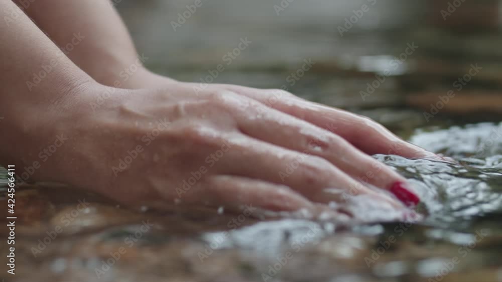 Female with red nails hands grabbing and lifting clear water from a river in slow motion Female with red nails hands grabbing and lifting clear water from a river in slow motion