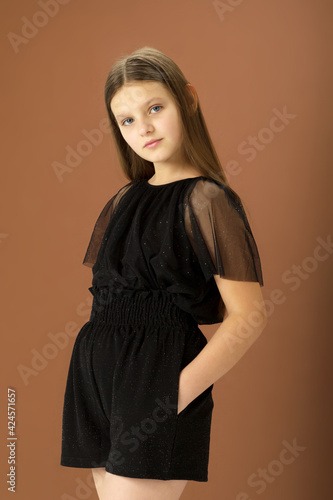 Cute girl posing in black jumpsuit. Photo session in the studio