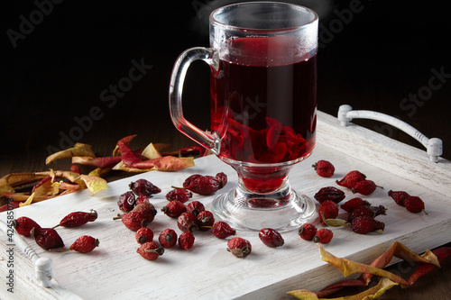 Hot winter drink surrounded by dried rose hips and apples