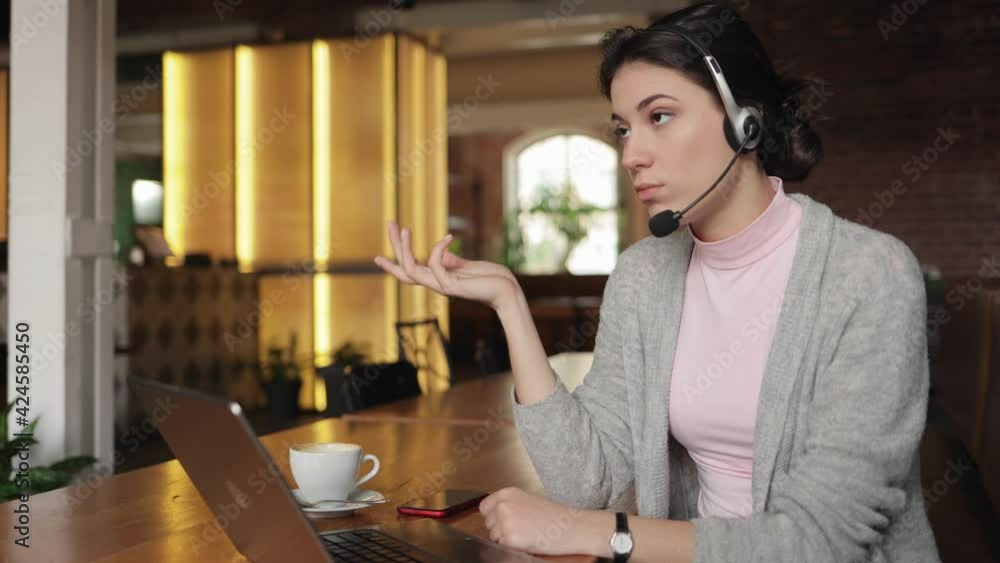 Young brunette business female wear wireless headset video conference calling on laptop computer talk by webcam in online chat, customer support service and distance online teaching concept. Freelance Young brunette business female wear wireless headset video conference calling on laptop computer talk by webcam in online chat, customer support service and distance online teaching concept. Freelance