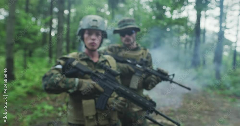 Squad of soldiers patrolling across the forest area, team with male and female soliders in dense forest with smoke in backgorund Squad of soldiers patrolling across the forest area, team with male and female soliders in dense forest with smoke in backgorund
