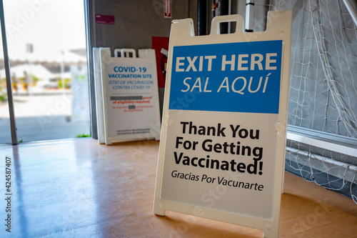 "Exit here. Thank you for getting vaccinated" portable plastic sign and pathway signage leading crowds of people to the exit during the covid-19 pandemic vaccination days