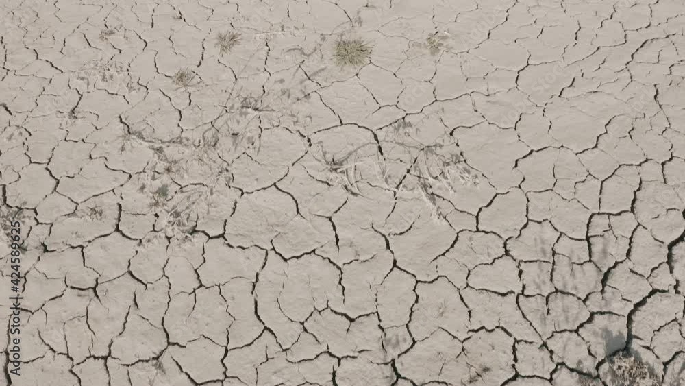 Dynamic shot of cracked soil ground of dried lake or river in mountains. Land destroyed by erosion and global warming - ecological issues concept Dynamic shot of cracked soil ground of dried lake or river in mountains. Land destroyed by erosion and global warming - ecological issues concept