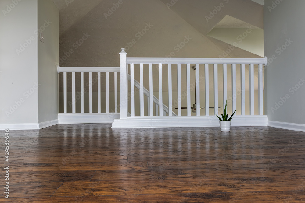 Empty second floor den with staircase railing and wooden laminated floor. Small potted cactus in the corner. Can be used as a background for virtual furniture or decor. Empty second floor den with staircase railing and wooden laminated floor. Small potted cactus in the corner. Can be used as a background for virtual furniture or decor.