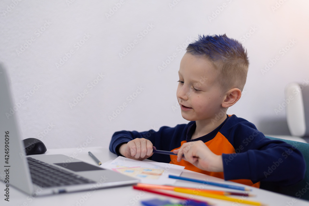 Distance learning and online education. Schoolboy boy studies at home and does school homework. Remote learning during corona pandemic Distance learning and online education. Schoolboy boy studies at home and does school homework. Remote learning during corona pandemic